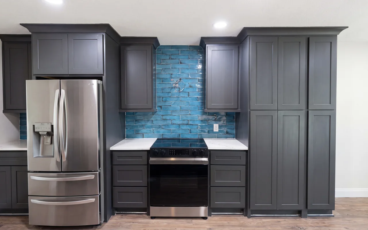 Blue glazed-brick kitchen backsplash with charcoal cabinets and quartz counters